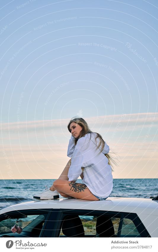 Relaxed woman on roof of car at seaside traveler relax vacation wanderlust adventure sunset female evening summer sundown nature tourist twilight holiday sky