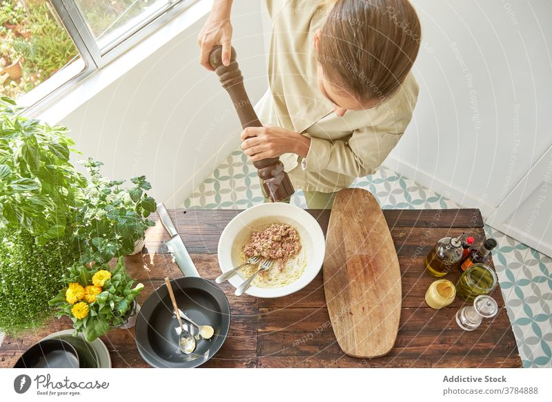 Woman cooking Steak tartare at home pepper mill seasoning add woman steak tartare raw meat beef uniform chef food prepare kitchen cuisine meal bowl mustard