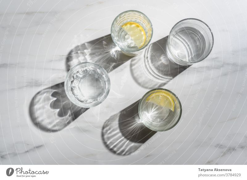 Glass of water with lemon pieces on marble background. Immune boosting morning drink fresh fruit glass cold citrus beverage