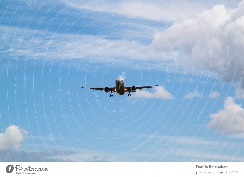 white passenger plane comes in to land with natural background of white clouds and blue sky air aircraft airline airliner airplane airport aviation business