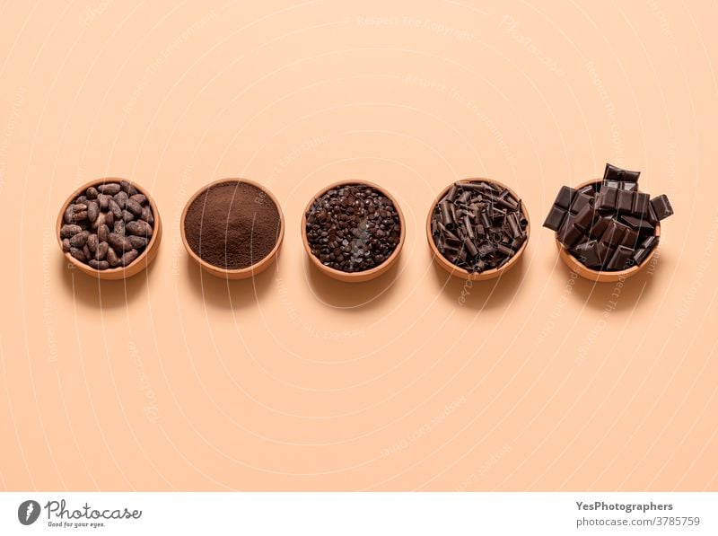 Cocoa and chocolate ingredients in bowls. Cacao beans and chocolate assortment top view above view aligned background baking beige bitter cacao cacao beans