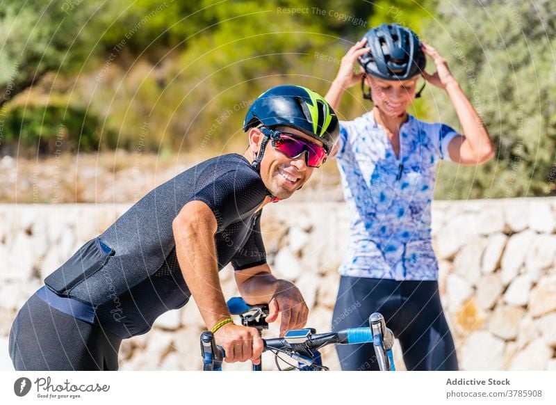 Cheerful bicyclists couple helmet active happy woman prepare sporty protect cheerful ride young female laugh safety lifestyle smile put on adjust activity