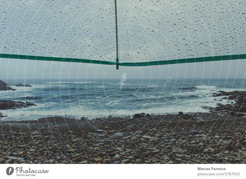 view of the coast with umbrella with raindrops water drop scene nobody alone shore dramatic protection waves coastline natural thunderstorm weather rainy autumn