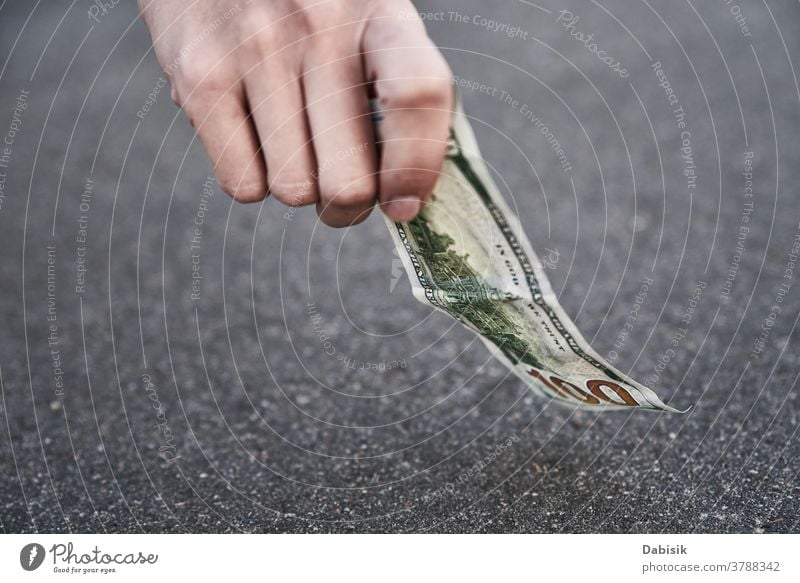 Hand pick one hundred dollar banknote from ground. Found money concept lost find street outdoor sidewalk person drop road cash bill woman currency hand luck