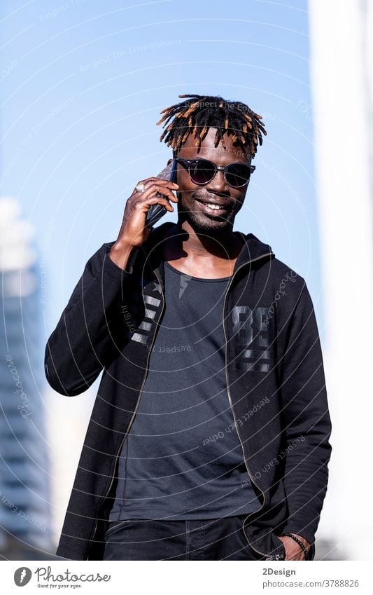 Black smiling man with sunglasses using mobile phone outdoors african black people male adult guy lifestyle happy photogenic 1 young technology casual attire