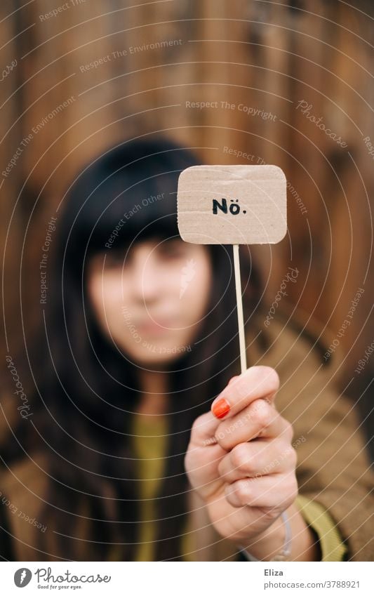 A dark-haired woman is holding up a sign saying "No". Refusal, say no, defiance. Nope. Cancelation protest Communicate refusal no means no Despite Characters