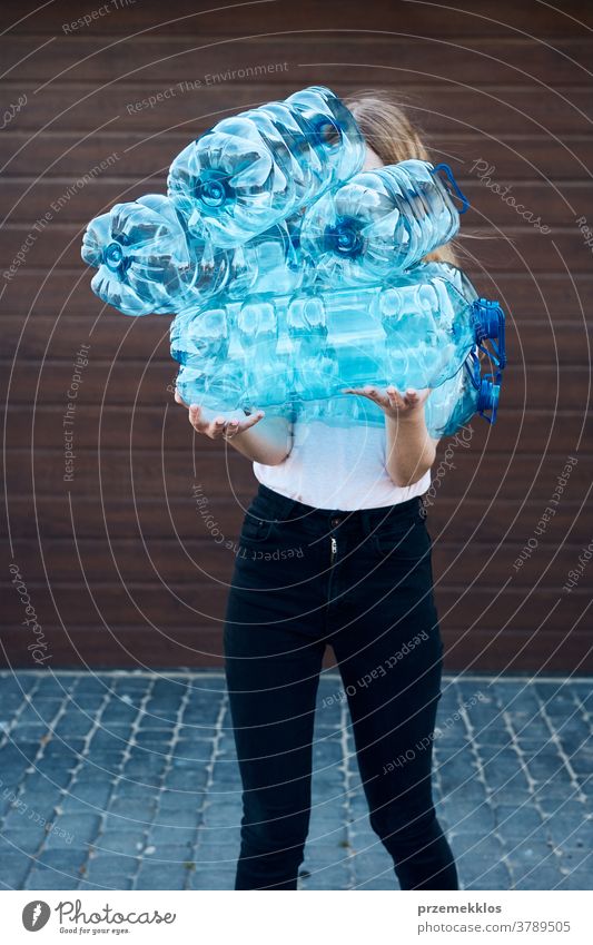 Young woman throwing out empty used plastic water bottles into trash bin blue collect collecting container crushed disposal ecology environment female garbage