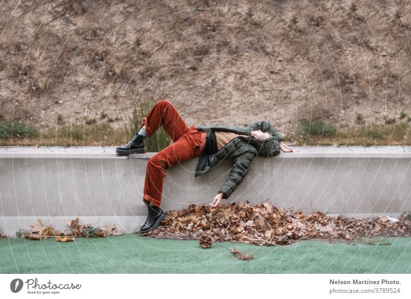 Portrait of a woman lying on the side of the road. Next to her are autumn leaves. portrait caucasian Autumnal Nature Colour photo Exterior shot Autumnal weather