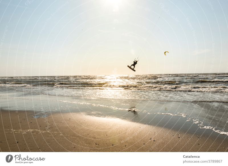 Kiter on the beach rises from the water into the air Beach Blue Sand Sandy beach Kitesurfing vacation Sports Ocean Horizon Sky North Sea Waves Surf coast Sun