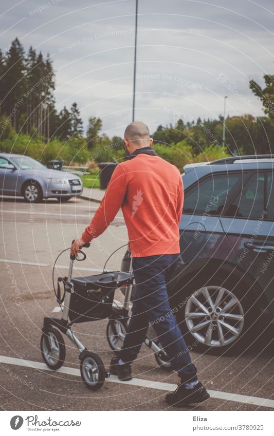 A young man pushes a walker in a parking lot to the trunk of a car Rollator Young man Walking aid Trunk Parking lot Carer Assistant Disability care Mobility