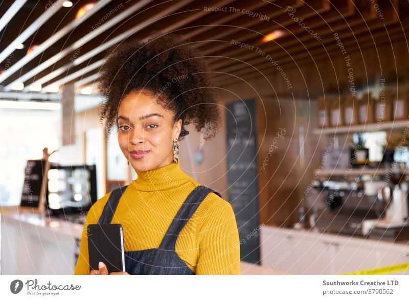 Portrait Of Female Business Owner Of Coffee Shop In Mask Using Digital Tablet During Health Pandemic business small business owner coffee shop cafe