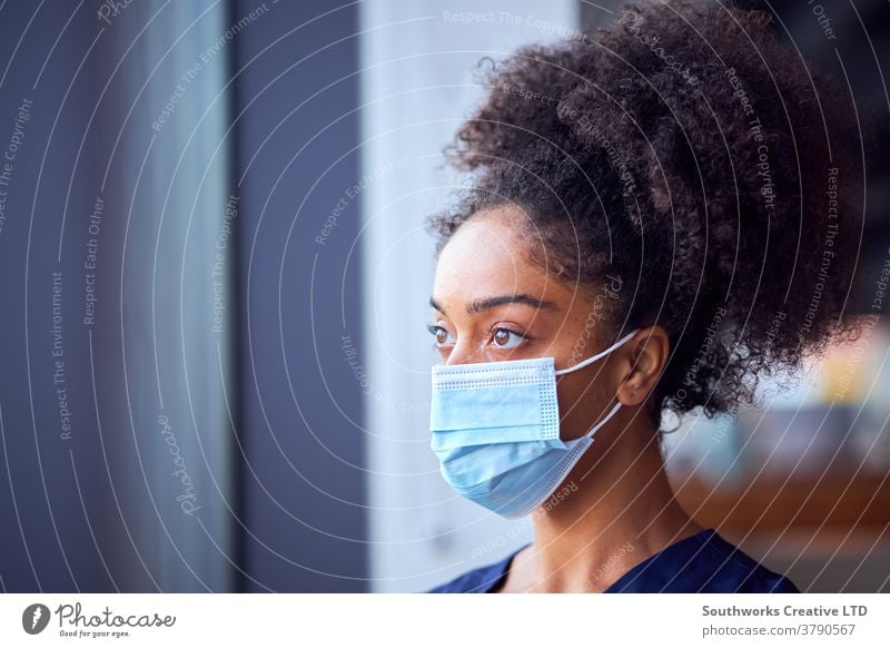 Female Doctor In Face Mask Wearing Scrubs Under Pressure In Busy Hospital During Health Pandemic doctor nurse scrubs key worker female woman wearing face mask