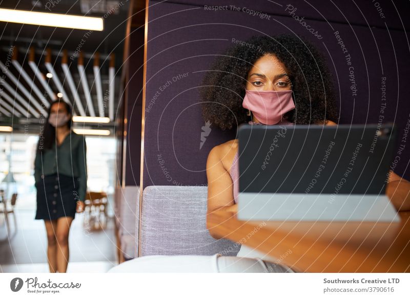 Businesswoman Wearing Mask Working In Socially Distanced Cubicle In Office During Health Pandemic business businesswoman face mask face covering ppe office