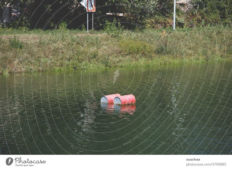 2 nasty looking pollution looking red floating barrels in a water Body of water Water River bank ton be afloat red buoys Environmental pollution Lakeside