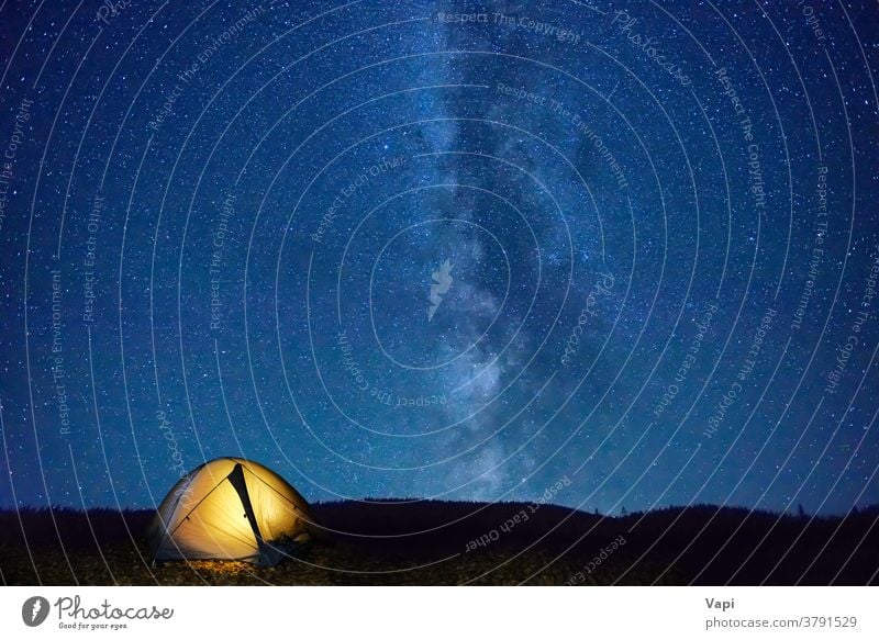 Illuminated tent in mountains night stars sky light landscape space hiking nature camp adventure yellow orange outdoors starry background travel illuminated