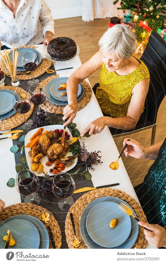 Anonymous friends eating delicious food during festive event menu dinner decoration christmas alcohol gather together meal home enjoy plate straw mat glass