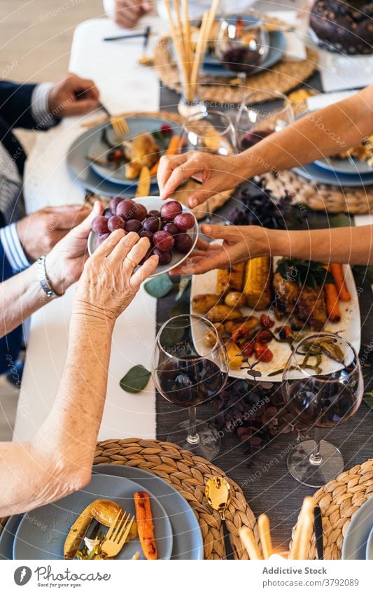 Crop woman taking delicious grapes during festive event dinner meal decoration christmas celebrate table wristwatch tasty fresh vitamin fruit portion food burn