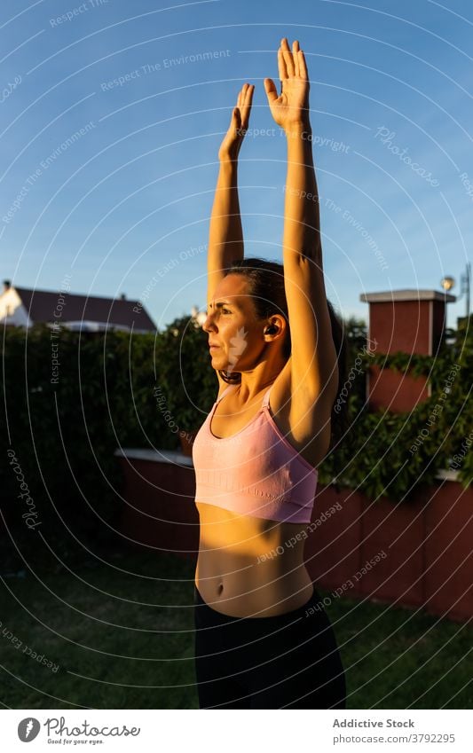 Sporty woman training in courtyard at sunset warm up stretch sportswoman breathe fit fitness female workout sportswear backyard wellness slim healthy athlete