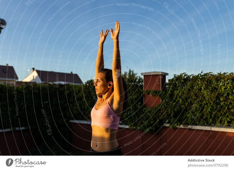 Sporty woman training in courtyard at sunset warm up stretch sportswoman breathe fit fitness female workout sportswear backyard wellness slim healthy athlete