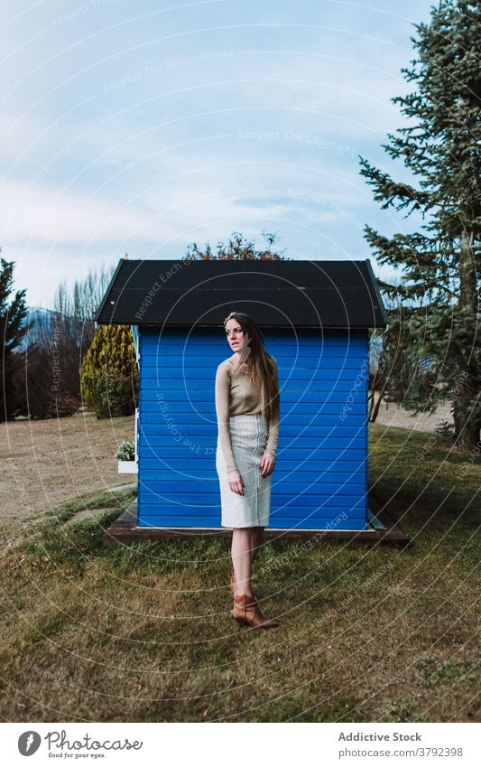 Unemotional woman in headband leaning on rural wooden structure positive style lean on elegant construction countryside gentle unemotional trendy nature