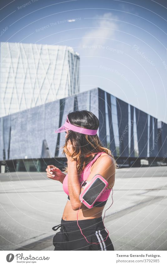 Girl listening to music on her armband with touchscreen and headphones in Barcelona activewear adult athletic girl running runner exercise cardio fitness woman