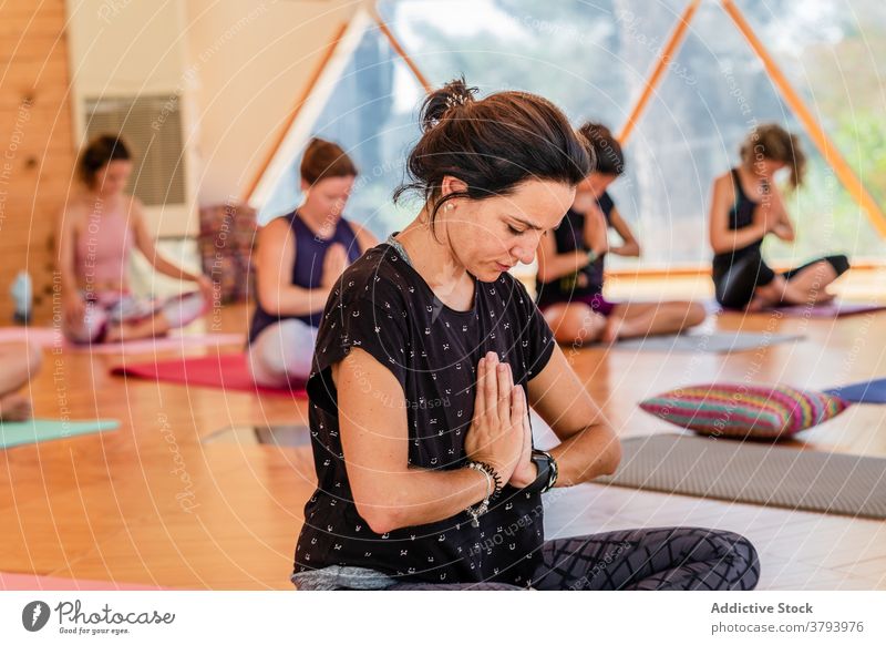 Women with prayer hands practicing yoga in lesson women practice namaste legs crossed spirit eyes closed stress relief mindful padmasana meditate reflective zen