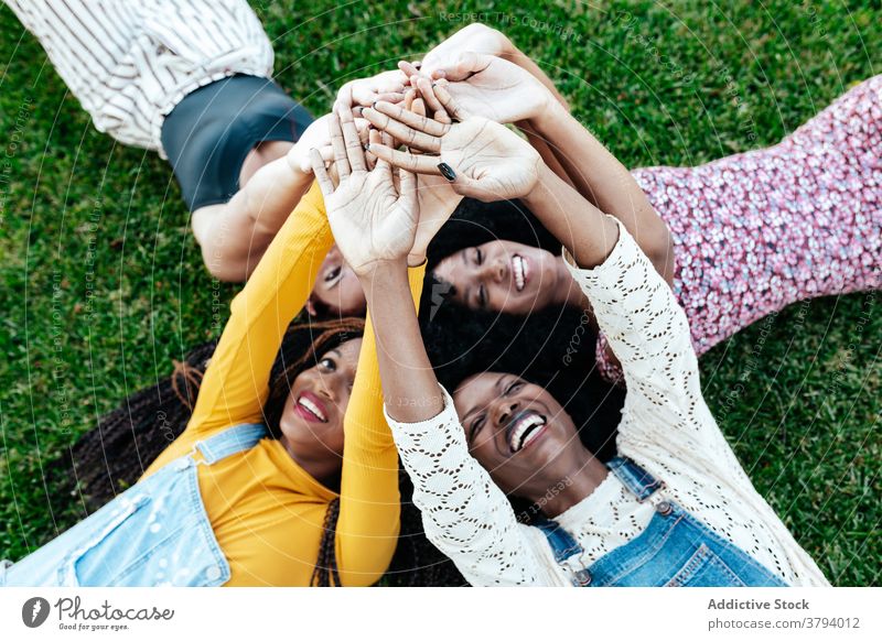 Carefree diverse women stacking hands together stack hands friendship unity company lying grass carefree multiethnic multiracial black african american park