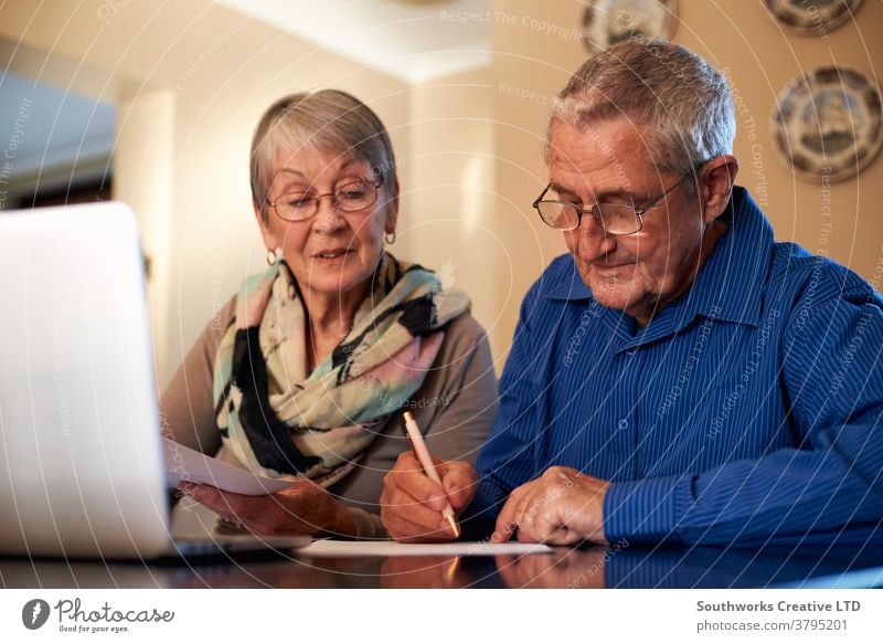 Senior Couple At Home Checking Personal Finances On Laptop couple senior seniors retired at home laptop technology computer online connected the internet