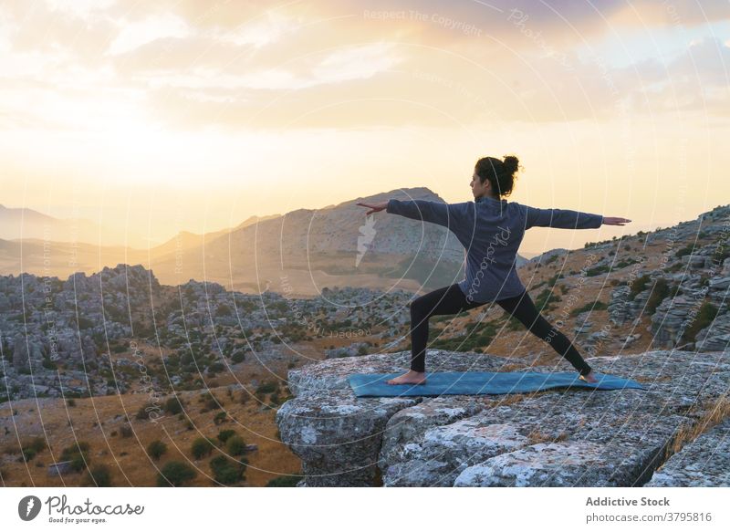 Concentrated woman practicing yoga in mountains at sunset rock nature practice asana pose position wellness harmony balance wellbeing zen health care