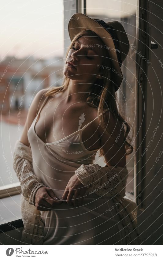 Sensual model in trendy wear near window sensual appearance style mindfulness eyes closed seductive feminine woman sensitive provocative reflective dreamy