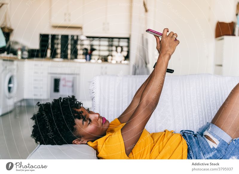 Laughing black woman taking selfie with smartphone at home using laugh having fun excited browsing mobile cheerful millennial young adolescent female modern