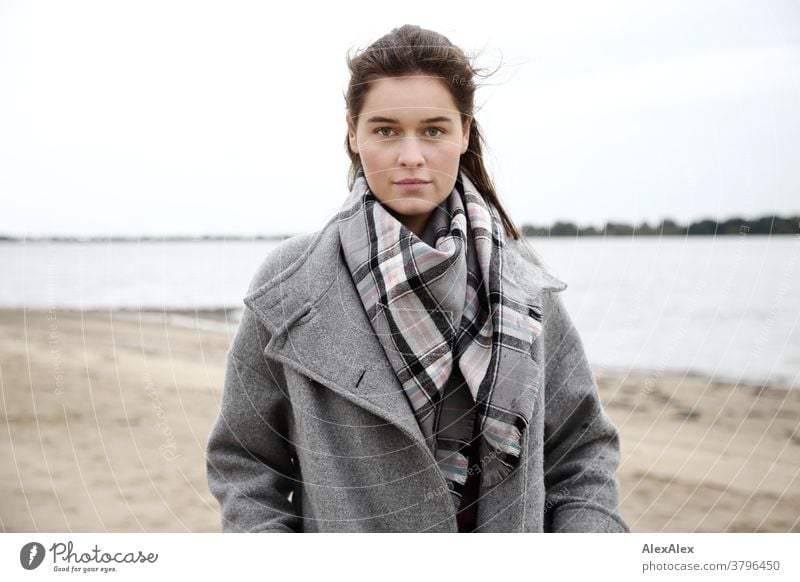 Close portrait of a young woman on the beach of the Elbe Woman Young woman 18-25 years warmly pretty Charming Slim Brunette long hairs Fresh Large smart