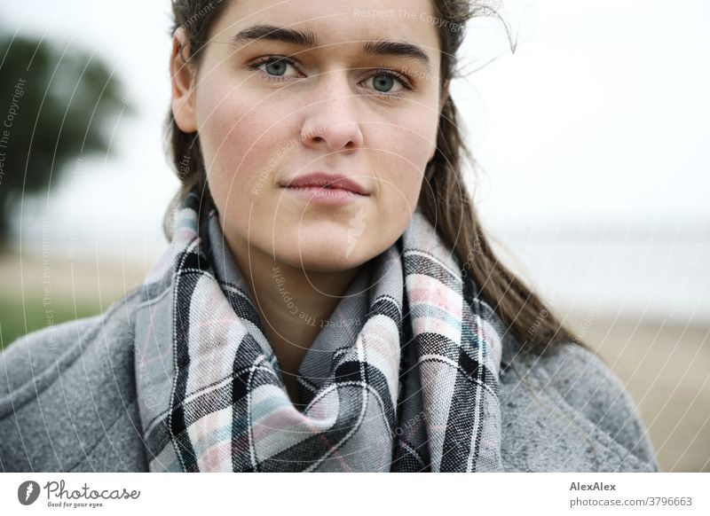 Close portrait of a young woman on the beach of the Elbe Woman Young woman 18-25 years warmly pretty Charming Slim Brunette long hairs Fresh Large smart