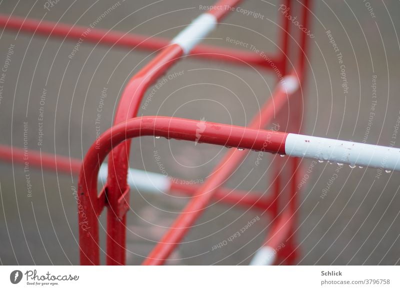 Construction site barrier in red and white criss-cross Construction site fencing cordon Red White Metal Crucifix Across shallow depth of field Rainy weather