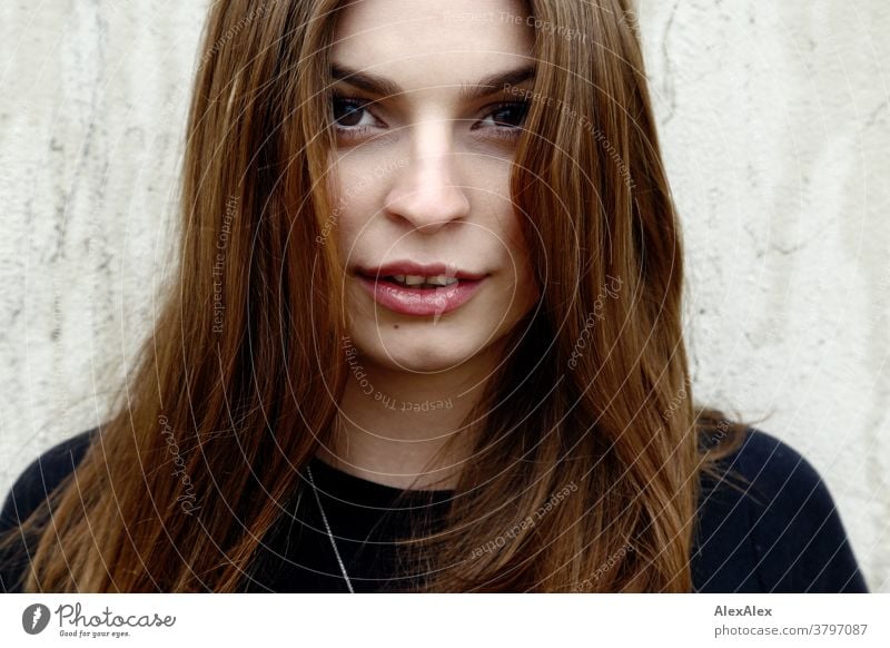 Close portrait of a young woman in front of a concrete wall Woman Young woman 18-25 years warmly pretty Charming Slim Brunette long hairs Fresh Large smart