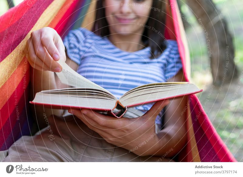 Relaxed woman reading book in hammock story enjoy summer lying park literature female interesting peaceful novel tranquil casual hobby nature recreation idyllic