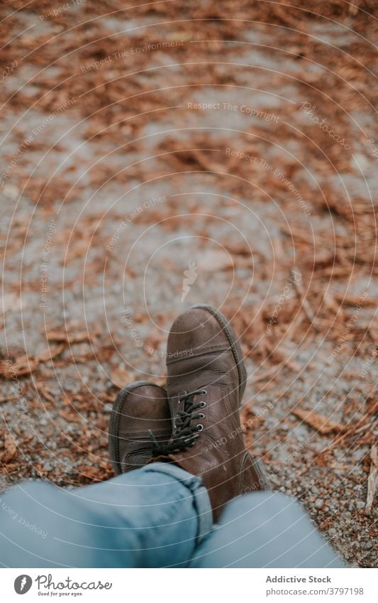 Crop traveler in boots in autumn park man footwear trekking season nature leaf male fall natural environment relax rest legs crossed style calm foliage sit