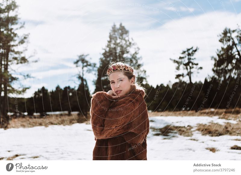 Elegant woman in fur wear and floral wreath standing in nature nordic tradition fashion style outfit feminine sensual dreamy wedding scandinavian charming