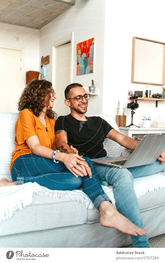 Happy couple having video conversation on laptop at home video call happy together holding hands sofa wave hand cheerful connection relationship boyfriend