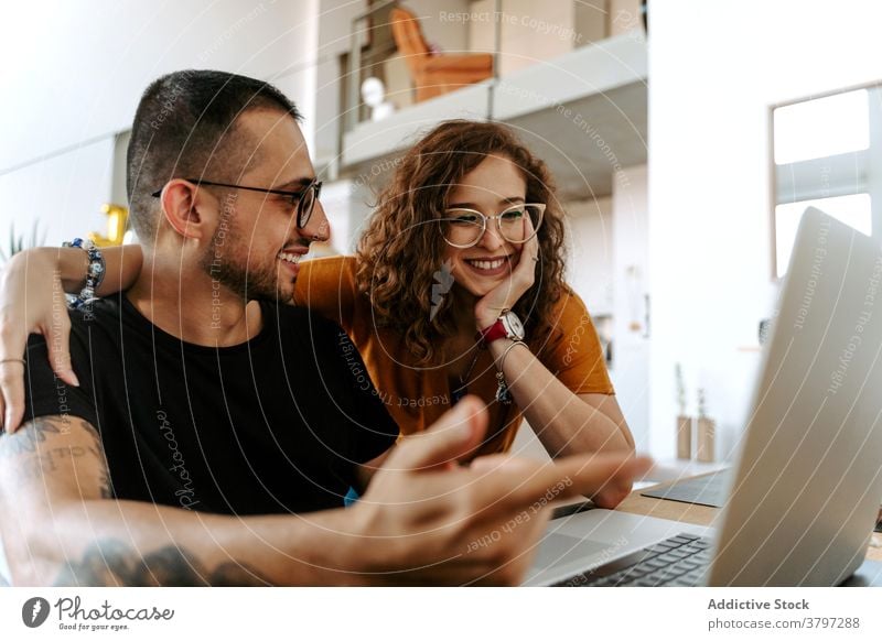 Happy couple having video conversation on laptop at home video call happy together holding hands sofa wave hand cheerful connection relationship boyfriend