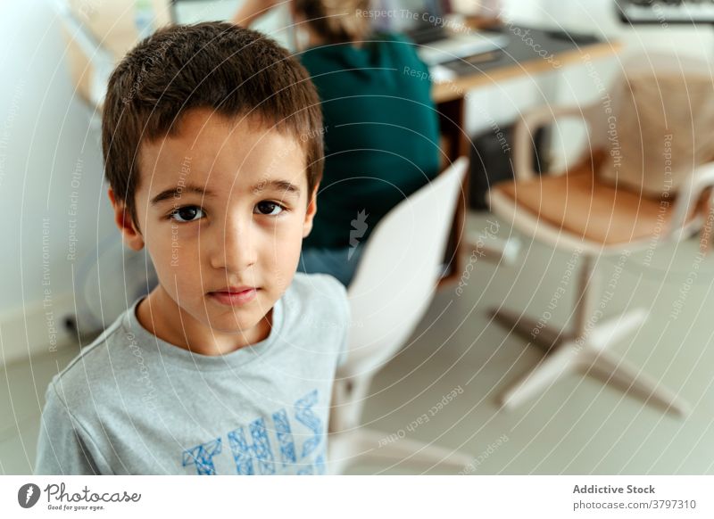 Positive boy standing in modern computer class positive content calm schoolboy smart education kid development gadget casual room workplace device contemporary