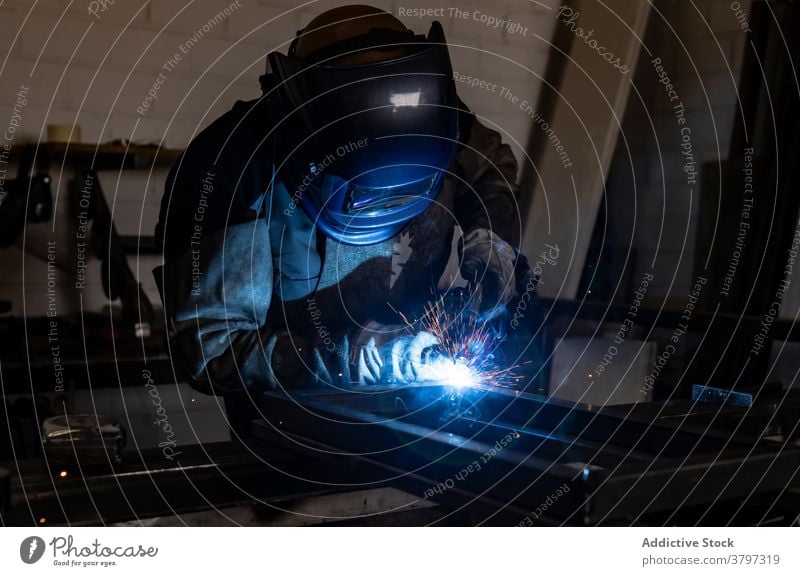 Professional welder in protective helmet in workshop metal man machine dark spark light male worker occupation professional tool industry job equipment labor