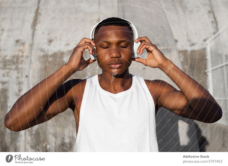 Black serious man listening to music in headphones calm eyes closed relax song athlete wireless sound male rest audio melody wellness tune concentrate wellbeing