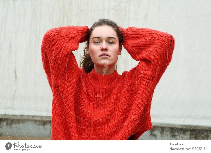 Close portrait of a young woman in front of a concrete wall Woman Young woman 18-25 years warmly pretty Charming Slim Brunette long hairs Fresh Large smart