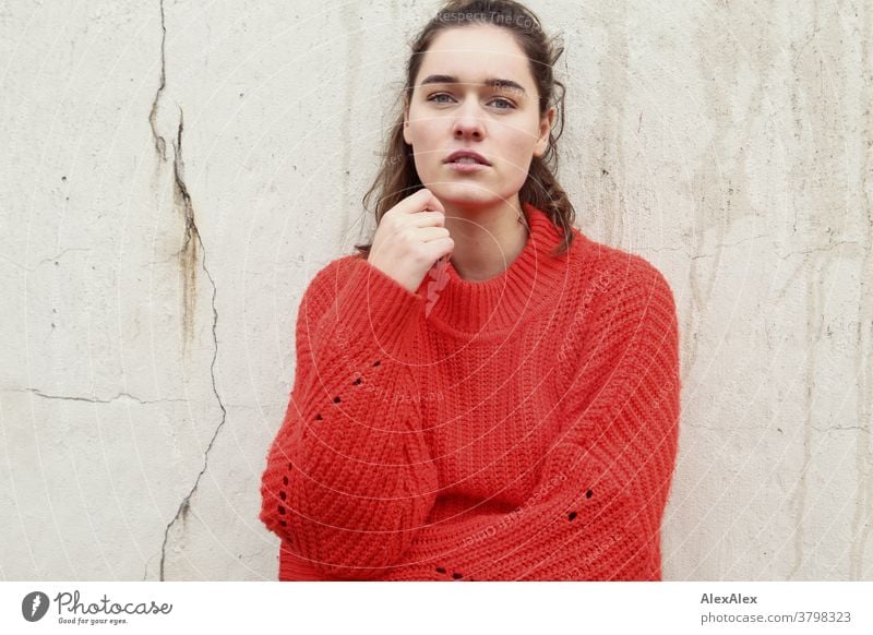 Close portrait of a young woman in front of a concrete wall Woman Young woman 18-25 years warmly pretty Charming Slim Brunette long hairs Fresh Large smart