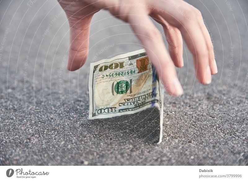 Hand pick one hundred dollar banknote from ground. Found money concept lost find street outdoor sidewalk person drop road cash bill woman currency hand luck