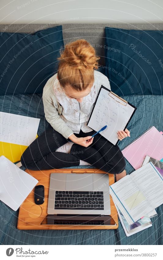 Student learning online, watching lesson remotely, listening to professor, talking with classmates on video call from home during quarantine accessories bed