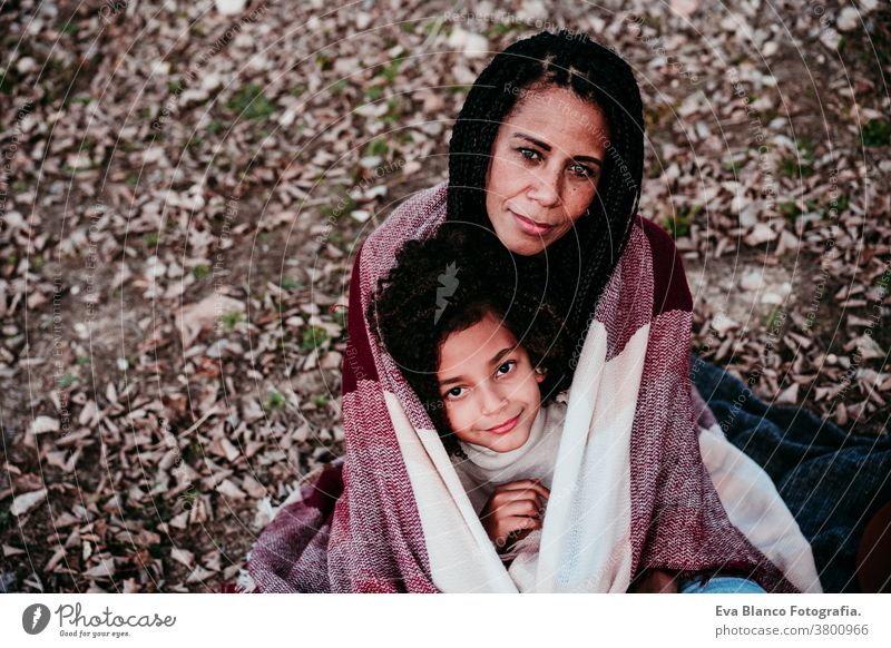 portrait of hispanic mother and afro kid girl outdoors relaxing in nature. Autumn season. Family concept daughter family mixed race motherhood childhood