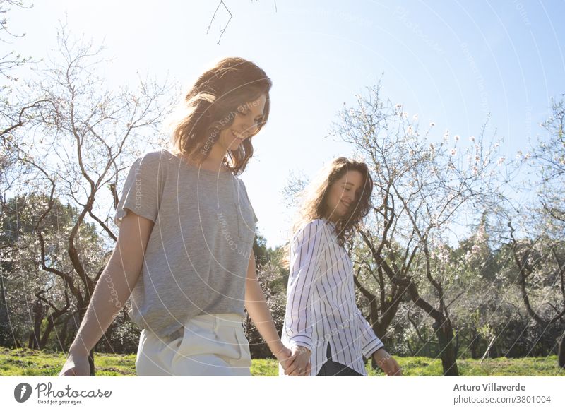 a couple of girls walk in a park hand in hand on a sunny day. They walk around smiling and happy activity background beautiful bright careless cheerful colorful