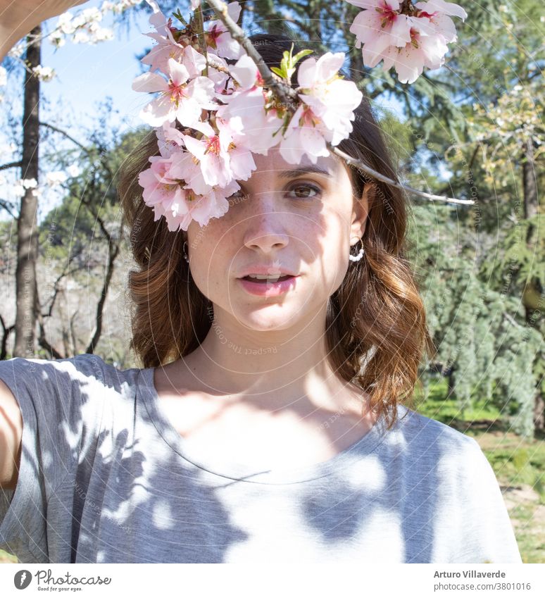 portrait of a woman in a park with flowering trees about to enter the spring adult aroma attractive beautiful beauty bloom brunette caucasian curly cute dress